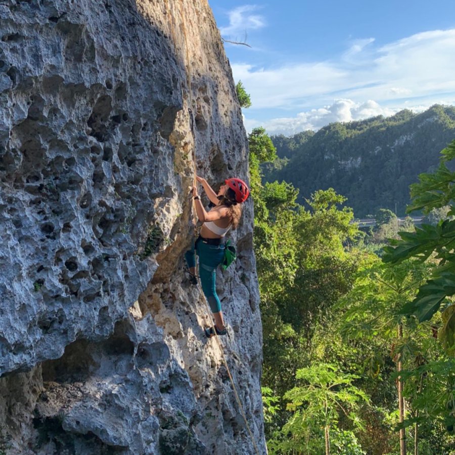 Mujer escalando roca kárstica.
