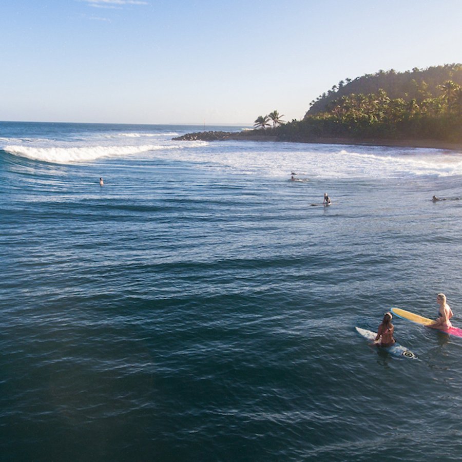 Local and visiting surfers in the water waiting for the next big wave at Domes Beach in Rincón, Puerto Rico.