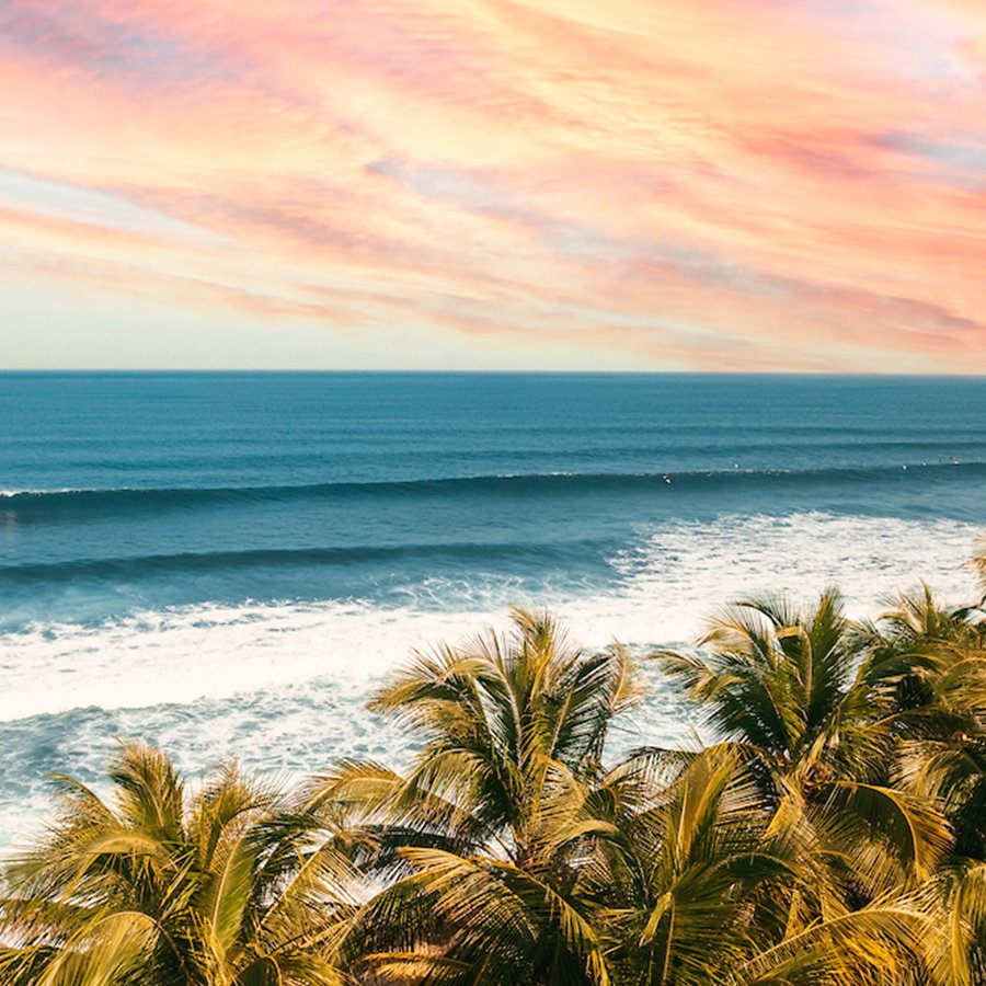 The sun setting, painting the sky a color of orange and pink, over the pristine waters of the beaches in Aguadilla, Puerto Rico.