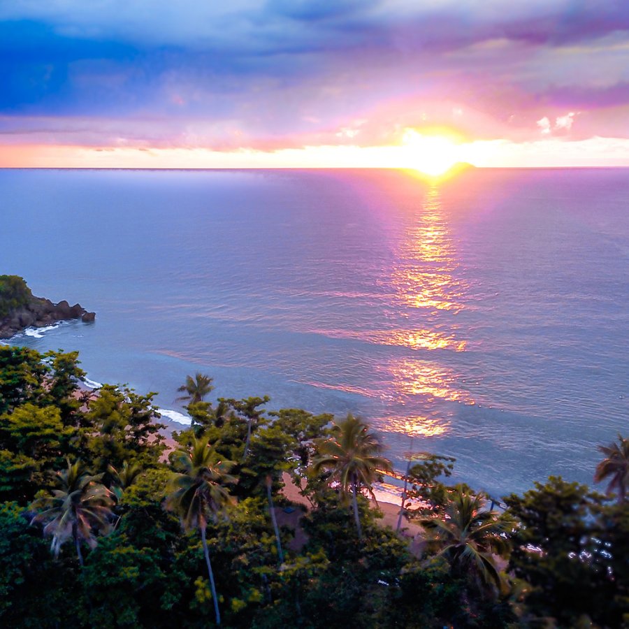 The sun setting over the water in Rincon, painting the sky a color of purple, pink, orange and dark blue.