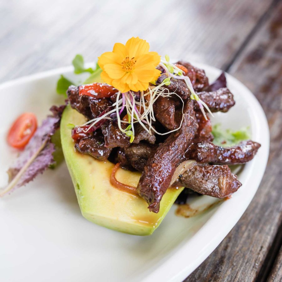 An avocado half is stuffed with strips of steak and other ingredients on a white plate at Buena Vibra in Cabo Rojo, Puerto Rico.