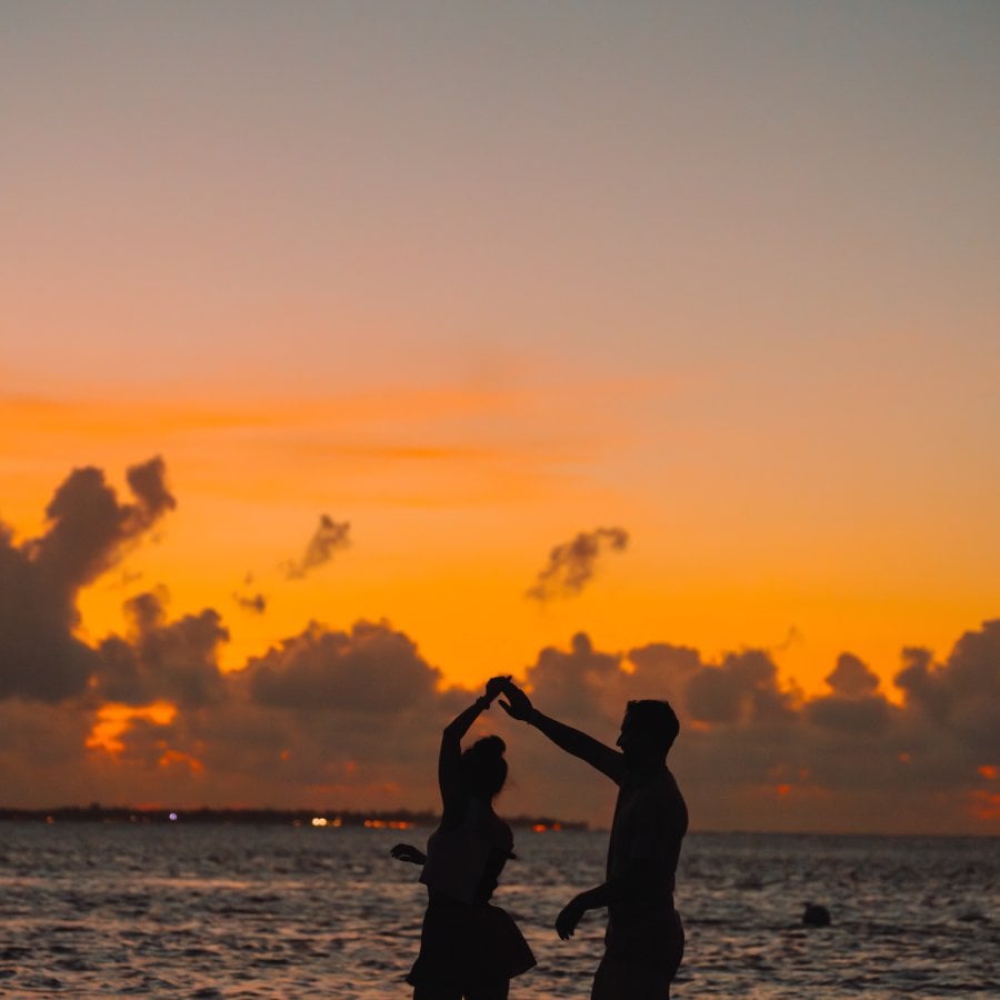 Pareja bailando en la playa al atardecer.