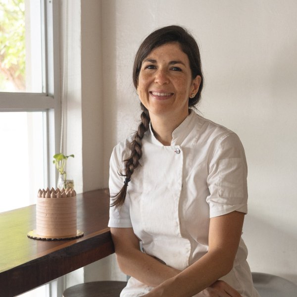 Chef Lucía at her patiserrie posing next to a cake.