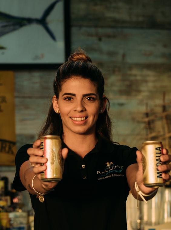 Un cantinero en San Juan sosteniendo dos latas de Medalla.