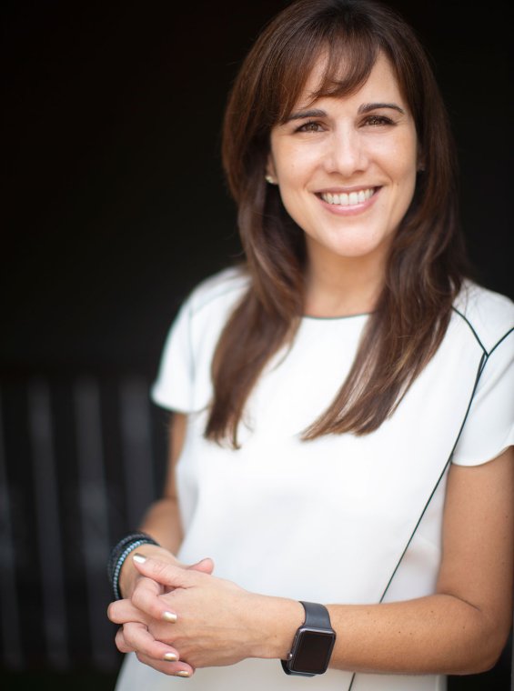 Cristina Villalon, a woman with long brown hair, stands in a doorway smiling.