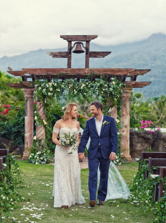 A newly married couple walks from the altar toward the camera with mountains in the background. Río Grande, Puerto Rico.