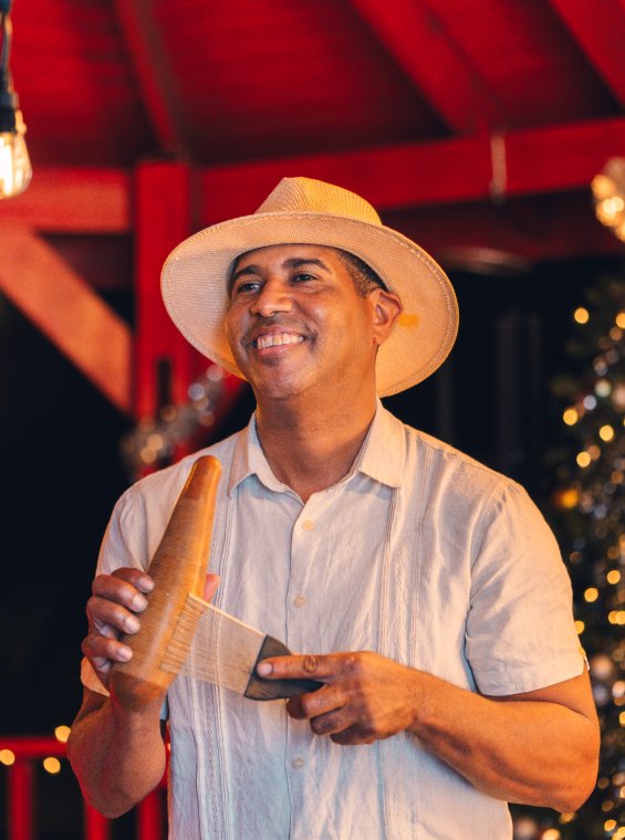 A person playing a güiro, a gourd shaped instruments